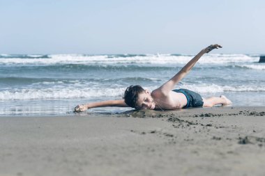 Sevimli genç çocuk sahilde eğleniyor