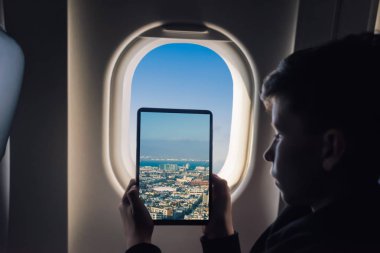 Beyaz çocuk uçak penceresinden San Francisco cityscape üzerinden fotoğraf çekmek tablet pc kullanarak. California. Abd