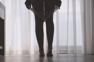 Seksi bacaklar perdelerin arka planında bir odada onu beyaz külot çıkararak güzel kadının siluet alt görünümü