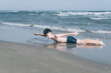 Sevimli genç çocuk sahilde eğleniyor