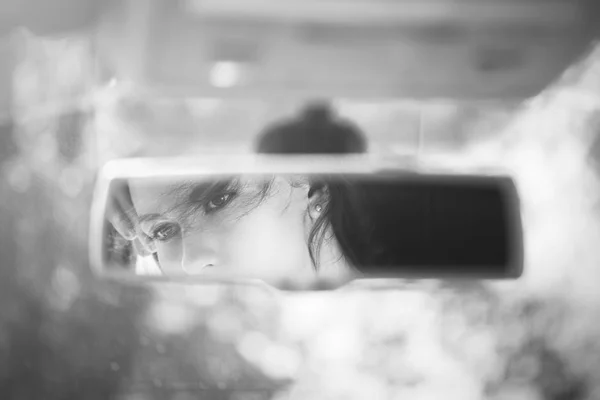 Black and white art picture of beautiful young woman face in the car rear view mirror. concept.