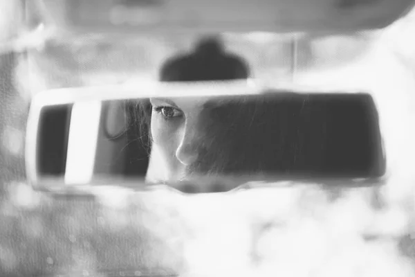 Black and white art picture of beautiful young woman face in the car rear view mirror. concept.