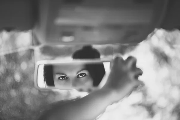 Black and white art picture of beautiful young woman face in the car rear view mirror. concept.