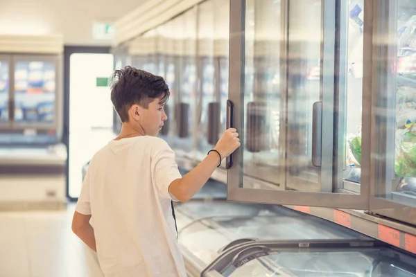 Хлопчик Супермаркеті Стоїть Перед Морозильною Камерою Біля Скляних Дверей — стокове фото
