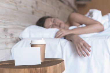 Uyuyan bir kız için bir sürpriz olarak yatak odasında masada duran metin için boş etiket ile kahve bir kağıt fincan. 