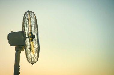 Açık bir günbatımı gökyüzü nün arka planına karşı elektrikli fan vantilatör. Kavram