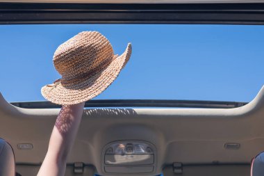 kız bir aracın açık ambarından onun hasır şapka dışarı trowing. Seyahat yaşam tarzı kavramı