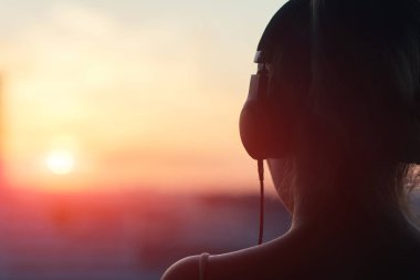 Günbatımında şehir içinde müzik dinlemek kulaklık kız 