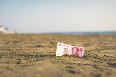 Sahilde kum bir Çin yuan değeri Banknot. Ucuz seyahat sigortası kavramı