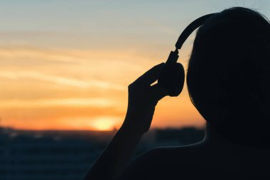 Günbatımında şehir içinde müzik dinlemek kulaklık kız 