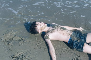 Sevimli genç çocuk sahilde eğleniyor