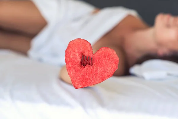 Beautiful girl in bed gives heart from watermelon on a fork. Concept