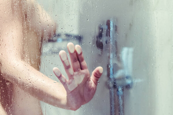Голая красивая женщина принимает душ за влажным туманным стеклом
.