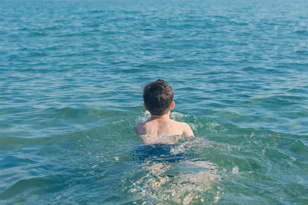 13 years old boy swimming and relaxation in the sea waves. Concept of family summer vacation
