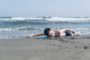 Sevimli genç çocuk sahilde eğleniyor