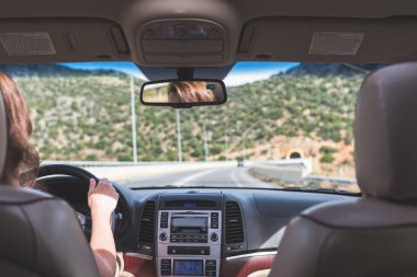 Kız İspanya'da otobanda araba kullanıyor. Arabanın arka koltuğundan ön cam, yol ve sürücü görünümü