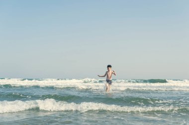 Sevimli genç çocuk sahilde eğleniyor