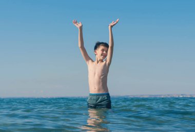 13 years old boy swimming and relaxation in the sea waves. Concept of family summer vacation clipart