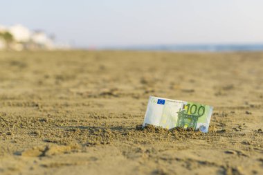 Sahilde kum yüz euro değerinde Banknot. Ucuz seyahat ve tatil kavramı. Promosyon ve indirim