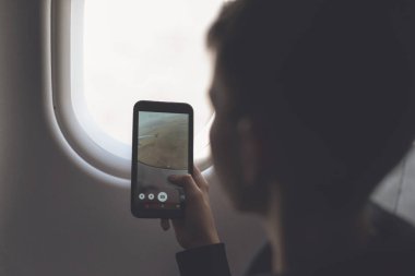 Beyaz çocuk akıllı telefon kullanıyor ve hava uçuşu sırasında fotoğraf çekiyor. Çocukla güvenlik yolculuğu. Kavram 