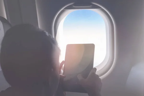 白人の少年はシートベルトを締め タブレットPcを使用して 空中飛行中に写真を撮ります 子供との安全旅行 — ストック写真