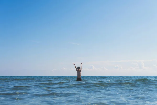 13 years old boy swimming and relaxation in the sea waves. Concept of family summer vacation