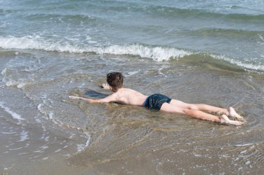 Sevimli genç çocuk sahilde eğleniyor
