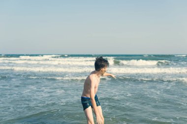 Sevimli genç çocuk sahilde eğleniyor