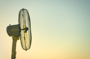 Açık bir günbatımı gökyüzü nün arka planına karşı elektrikli fan vantilatör. Kavram