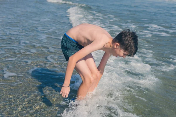 13歳の少年が海の波で泳いでくつろいでいます 家族の夏休みの概念 — ストック写真