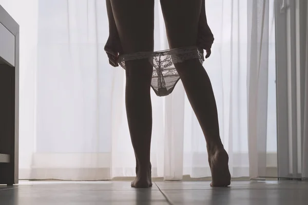 커튼을 배경으로 방에서 그녀의 팬티를 섹시한 다리와 아름다운 여자의 실루엣의 — 스톡 사진