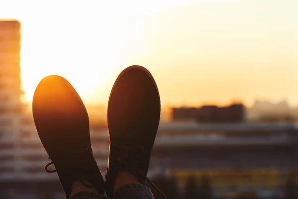 Male feet in shoes on the balcony. city and sunset background