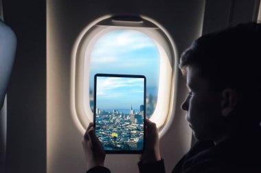 Beyaz çocuk gökdelenler ile uçak penceresi San Francisco cityscape üzerinden fotoğraf çekmek tablet pc kullanarak. California. Abd