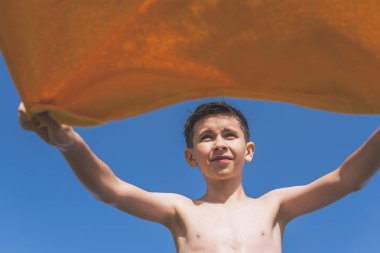 Bottom view on the boy with yellow towel on the blue sky background. Concept. clipart