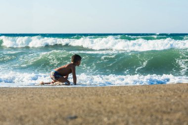 Mutlu neşeli çocuk denize oynarken eğlenmek ve su sıçramaları yapıyor 