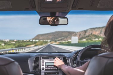 Kız Kıbrıs'ta otoyolda sürüyor. Arabanın arka koltuğundan ön cam, yol ve sürücü görünümü