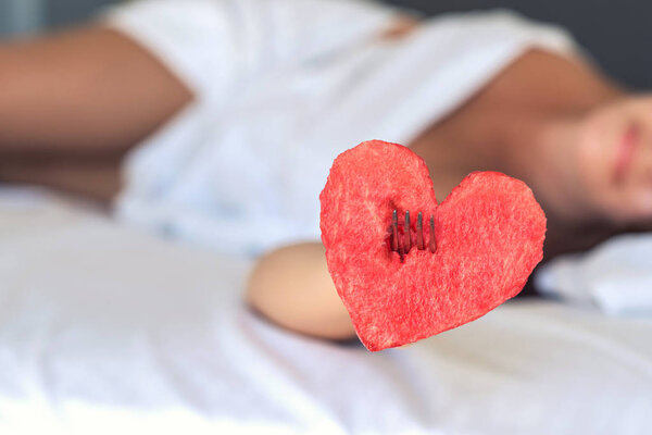 Beautiful girl in bed gives heart from watermelon on a fork. Concept
