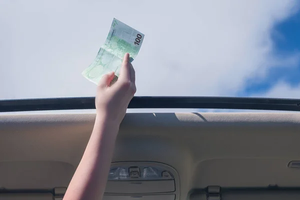 girl holds one hundred euro bill in open hatch of a car. Travel  concept