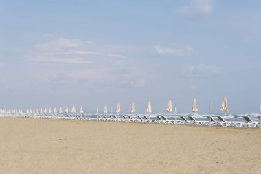 Larnaka şehrinde plaj mackenzie. Gün batımında deniz manzarası, şemsiyeler ve şezlonglar. Makenzy, Kıbrıs