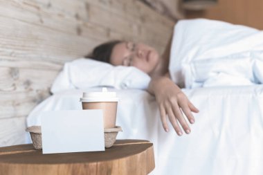 Uyuyan bir kız için bir sürpriz olarak yatak odasında masada duran metin için boş etiket ile kahve bir kağıt fincan. 