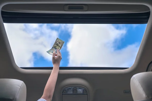 girl holds one hundred dollar bill in open hatch of a car. Travel  concept