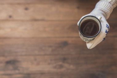 ahşap bir evin terasında kahve demir bir fincan ile kadın elleri. Kış konsepti