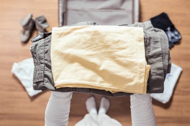 Yeni bir yolculuk için bir bagaj (bavul) bir yürüyüş için giysi ambalaj kadın elleri üst görünümü. 