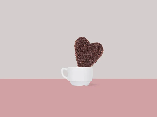 A huge cookie from ground coffee in the form of a heart in a coffee cup on  background