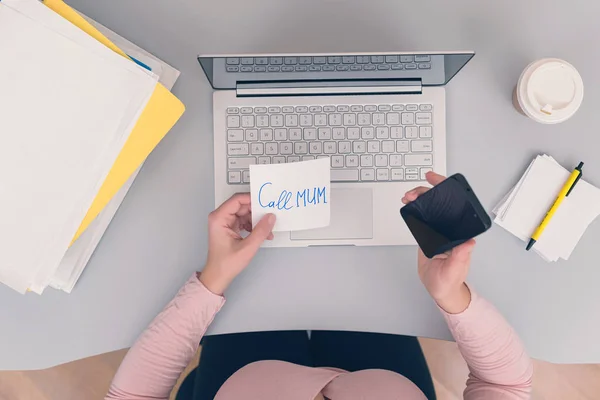 Woman clerk is sitting at office table holding note sticker with message \