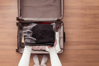 Yeni bir yolculuk için bir bavul (bavul) fitness giyim ambalaj kadın elleri üst görünümü. 