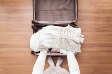 Yeni bir yolculuk için bir bavul (bavul) bir ceket ambalaj kadın elleri üst görünümü. 