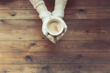 Arka planda eldiven ellerde kahve fincanı 