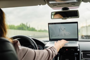 İş kadını otobanda sürüş ve dizüstü bilgisayar kullanarak çalışan araba acil stop düğmesini açmak. 