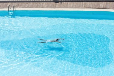 Şeffaf mavi su ile yüzme havuzunda çocuk havadan görünümü. Hareket halinde 